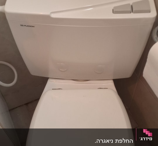 אסלה לבנה עם מיכל הדחה בחדר אמבטיה